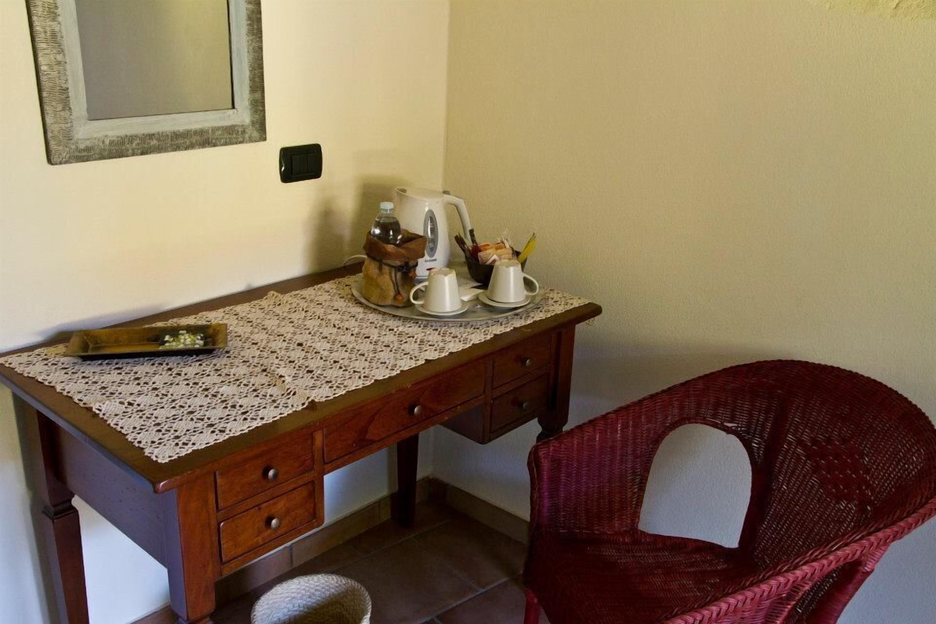A wooden desk with a lace tablecloth, a kettle, cups, and a basket.