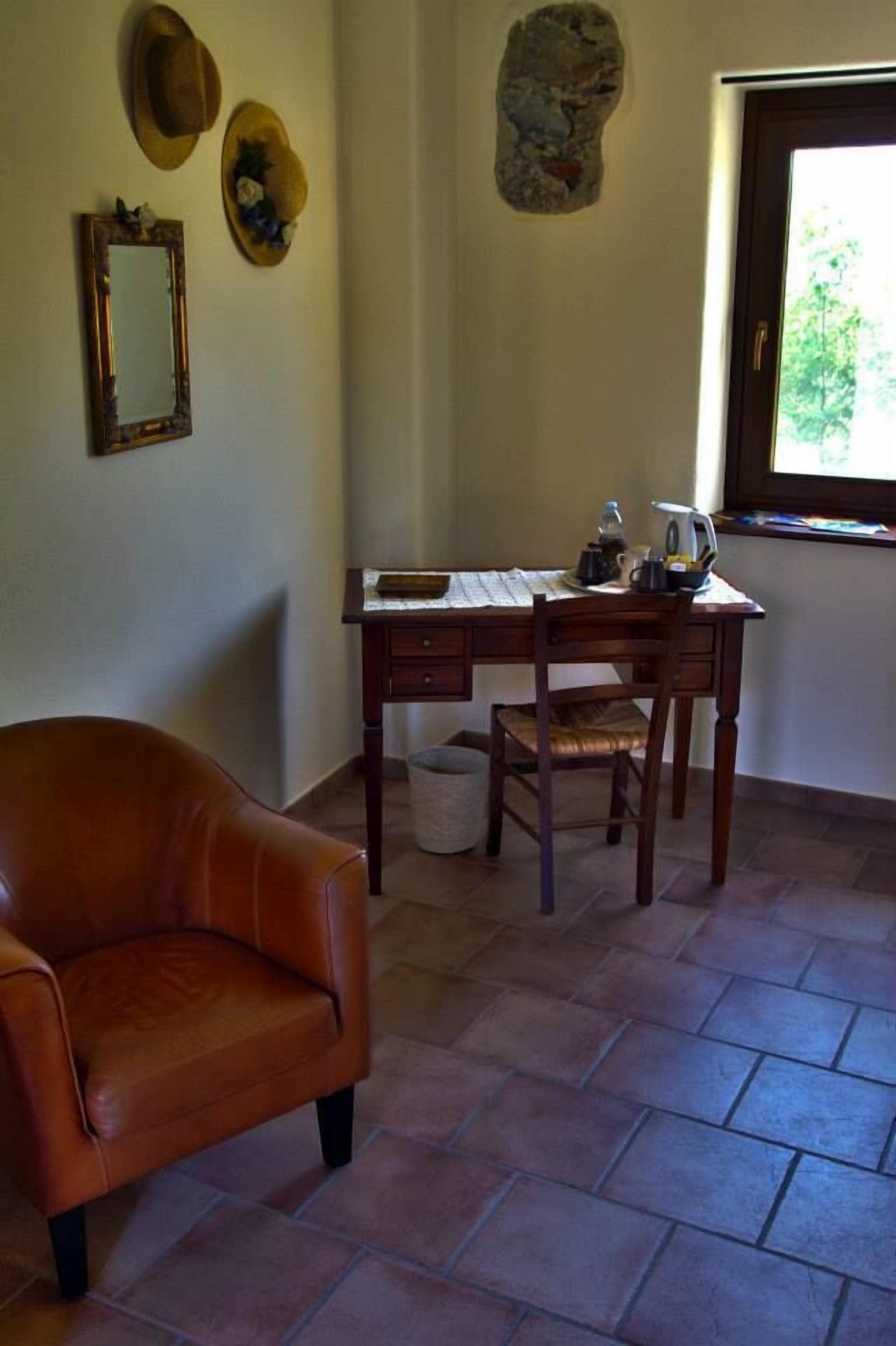 A room with a leather chair, a wooden desk, and a stone wall decoration.