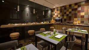Un restaurante moderno con una barra larga, varias zonas de estar y una pared de azulejos coloridos.