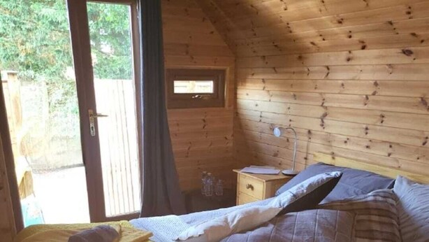 Un dormitorio acogedor tipo cabaña de madera, con cama, almohadas y mesita de noche.