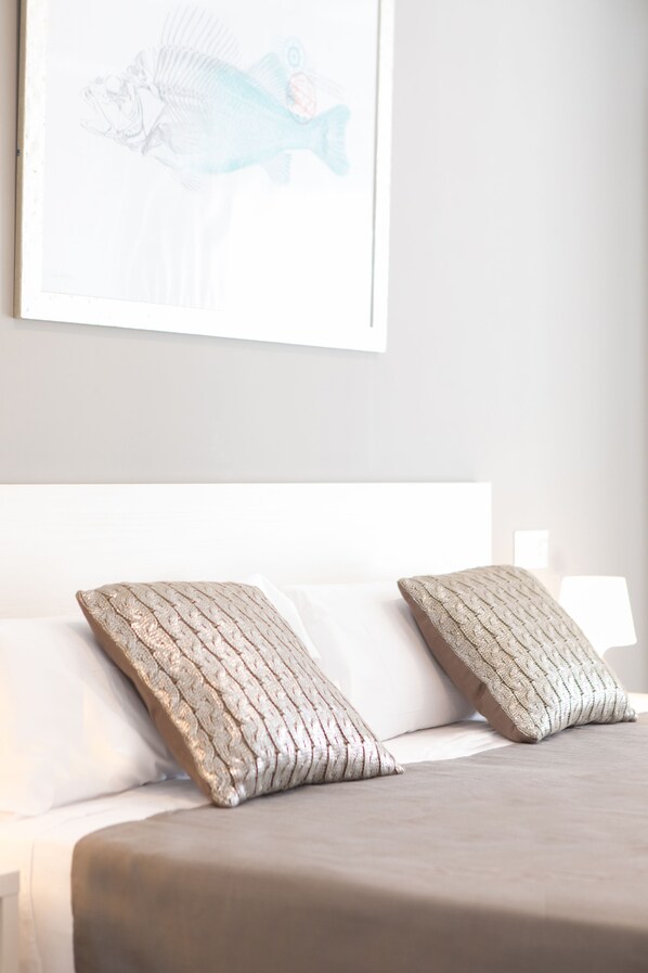 Un dormitorio con una cama, dos almohadas y una obra de arte en la pared de un pez.