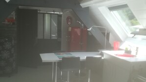 Una cucina con un tavolo da pranzo, sedie, una lampada a sospensione rossa e una finestra che lascia entrare luce naturale.