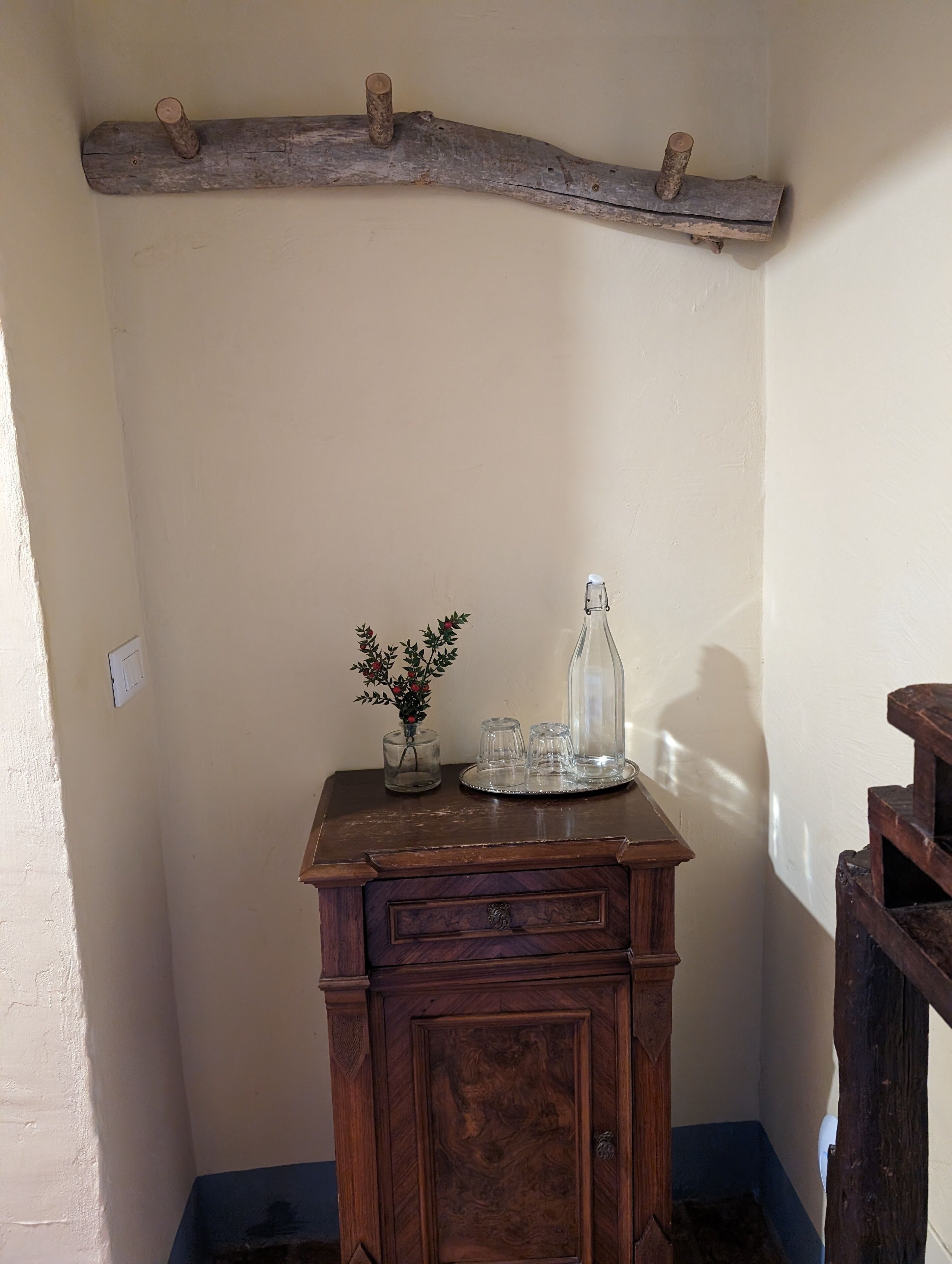 A wooden cabinet with a glass bottle and a small vase on top.