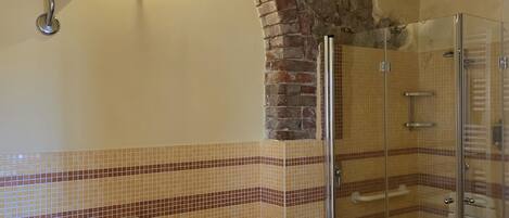 Un baño con pared de azulejos, ducha, inodoro y lavamanos.