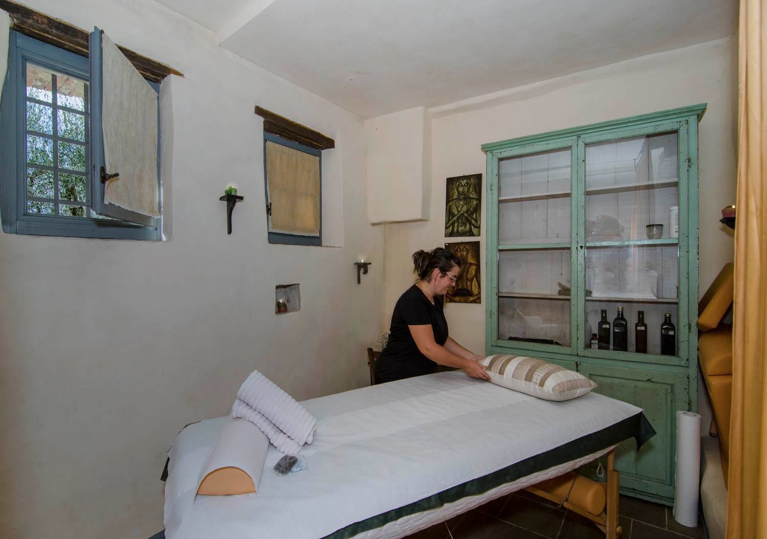 A room with a bed, a green cabinet with bottles, and a window with curtains.