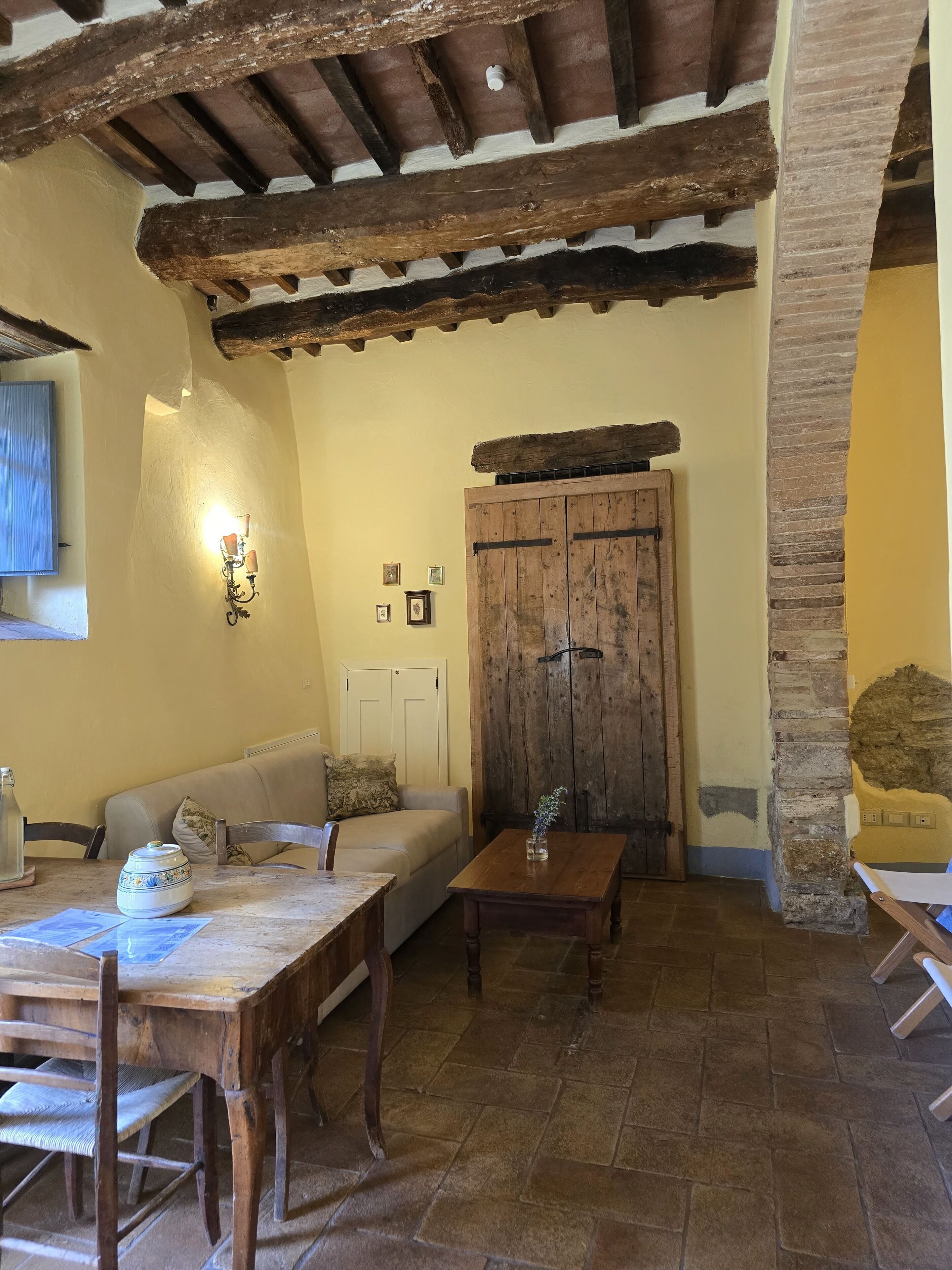 Un interno rustico con un tavolo di legno, un divano e un muro in pietra.