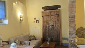 Un interno rustico con un tavolo di legno, un divano e un muro in pietra.