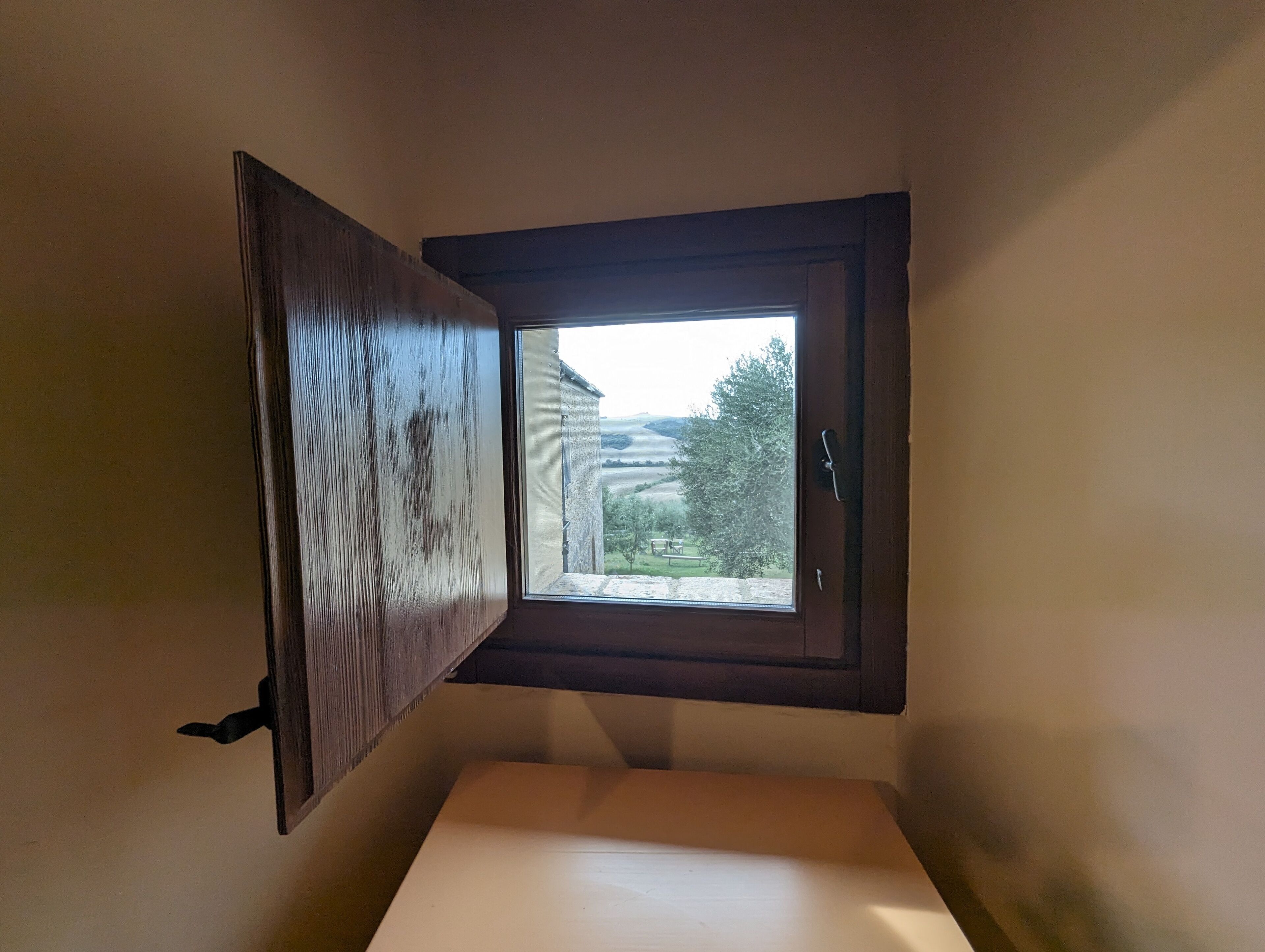 A corner room with a window overlooking a rural landscape.