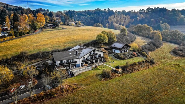A large house with a spacious deck and a driveway. - Hotel Landhaus Müllenborn (Gerolstein)
