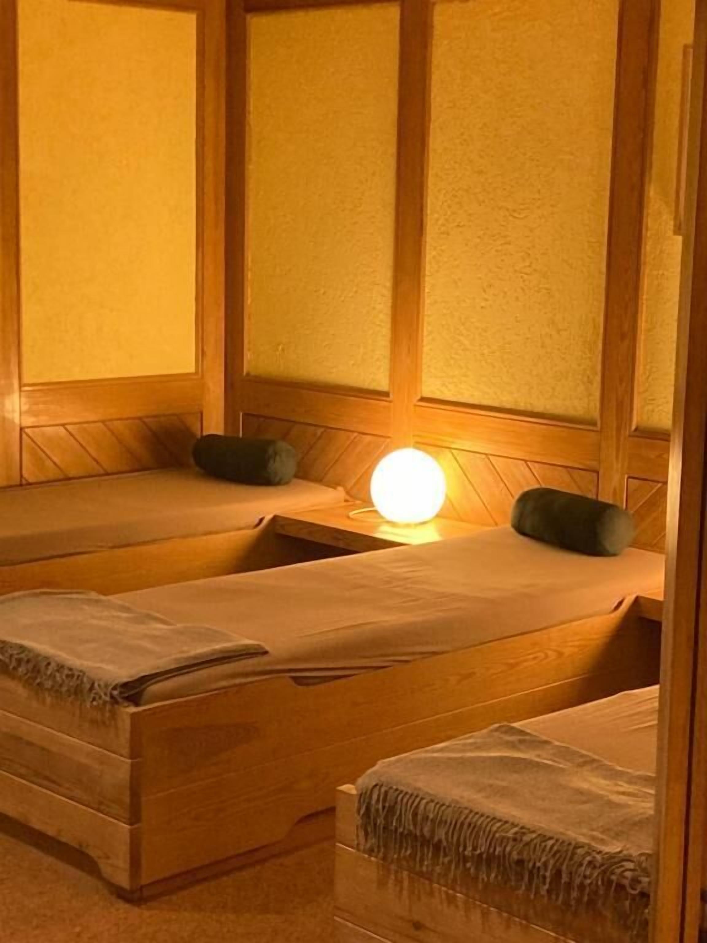 A room with two wooden beds, each with a pillow and a blanket.