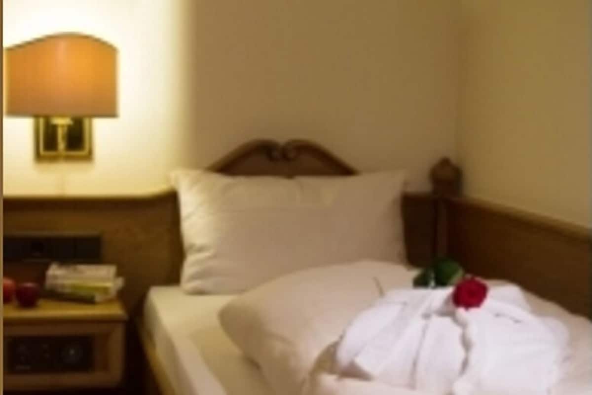 A hotel room with a bed, a nightstand, and a lamp.