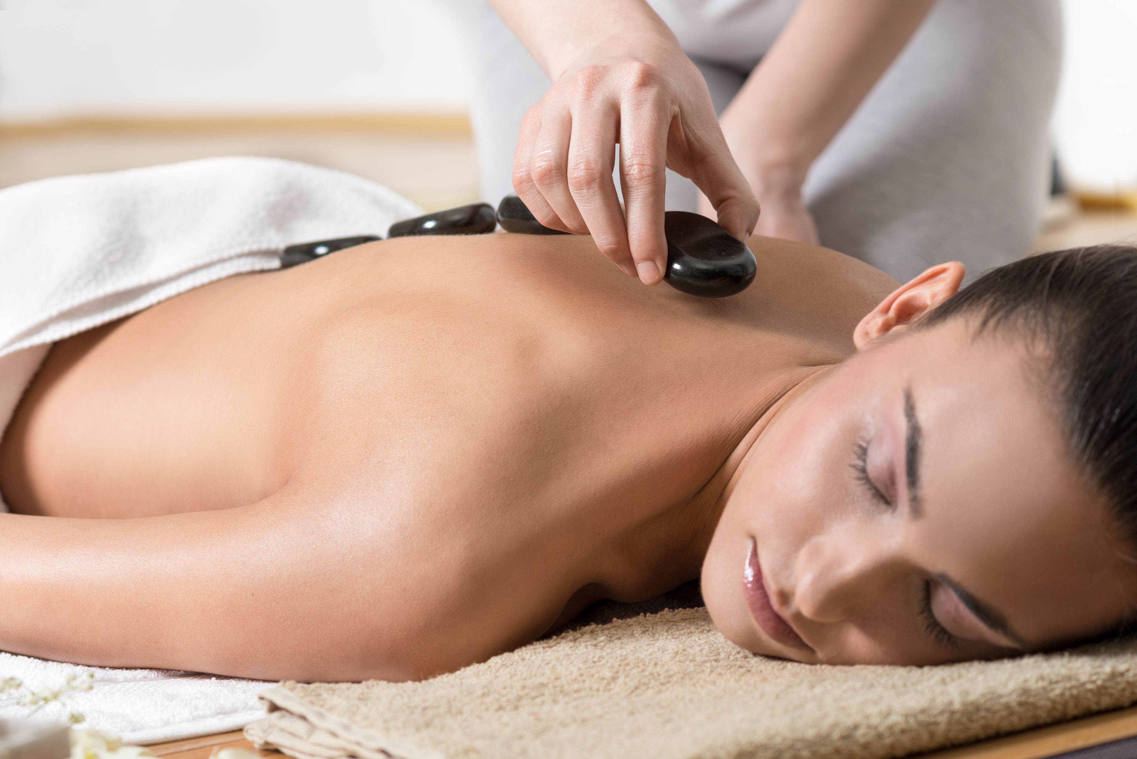 A person receiving a back massage with a stone on their back.
