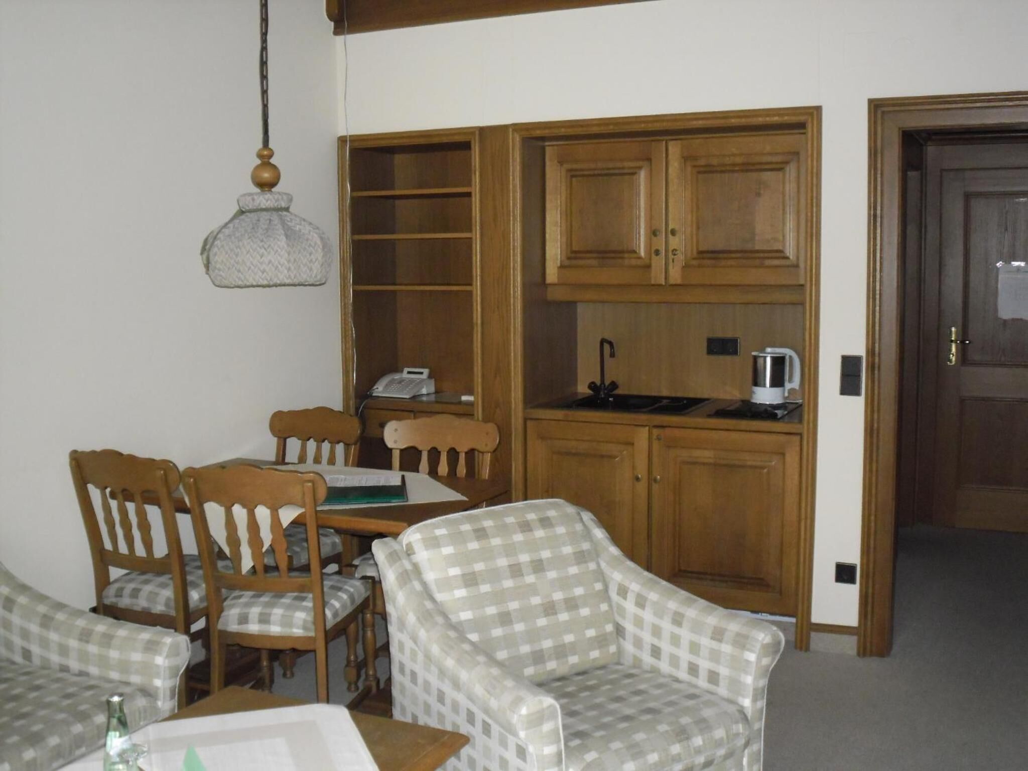 A compact living space with a dining area, a kitchenette, and a door leading to another room.