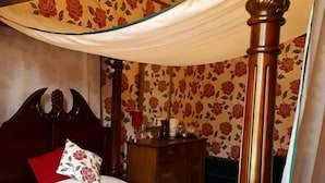A four-poster bed with a canopy, a wooden nightstand, and a red pillow. - Hallgreen castle (Montrose)