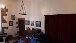 A cozy living room with a wooden table, a hanging light fixture, and a red curtain. - Hallgreen castle (Montrose)