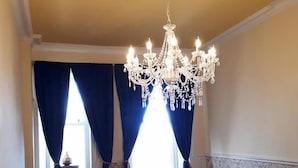 A staircase with a wooden handrail, a chandelier, and a window with blue curtains. - Hallgreen castle (Montrose)