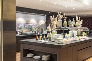 A buffet area with a variety of food items, plates, and decorative vases. - Parkhotel Heilbronn (Heilbronn)