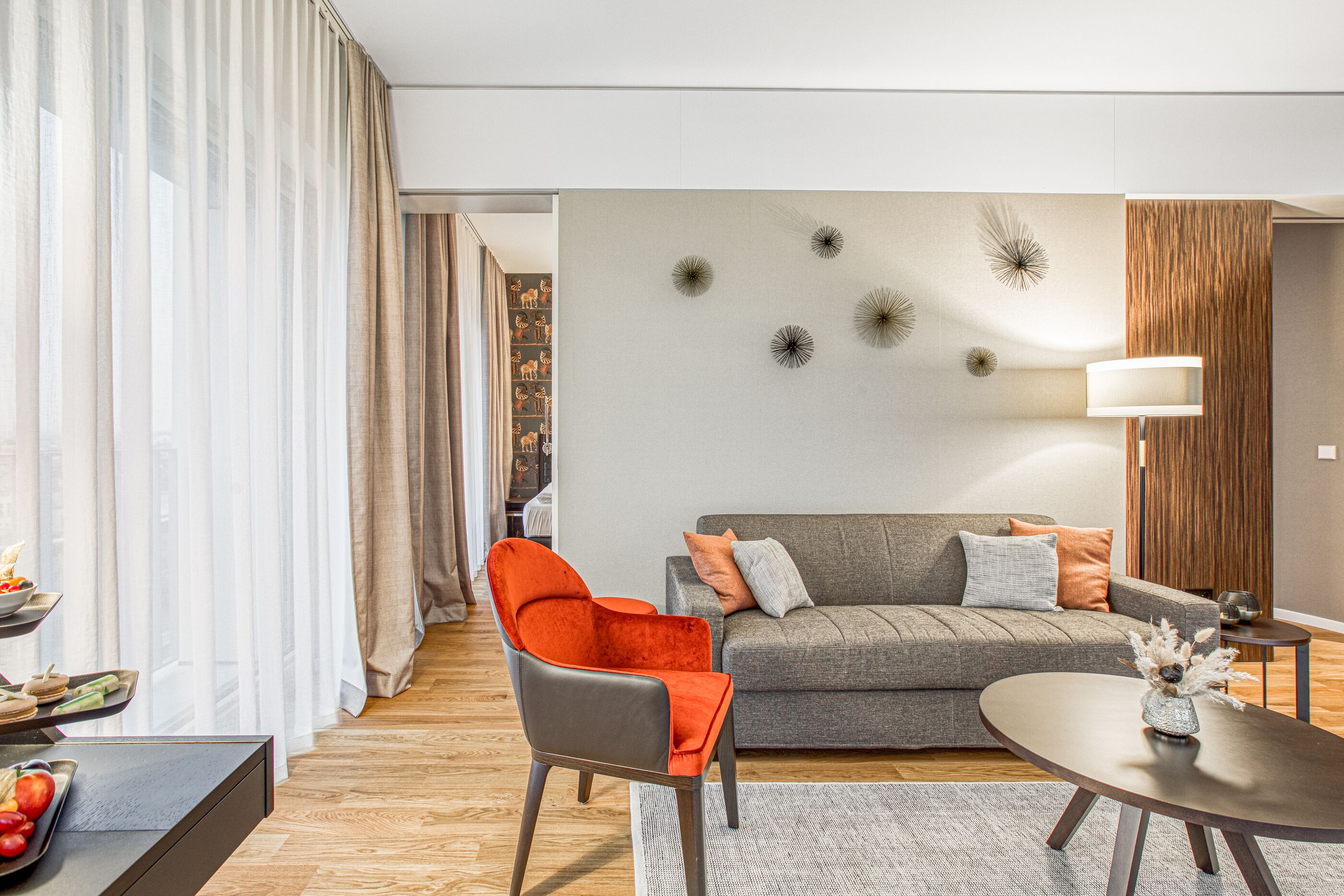 A modern living room with a grey sofa, orange chair, and a round coffee table.