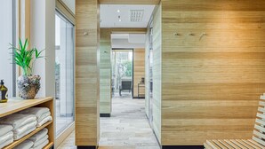 Un couloir d’hôtel moderne avec des murs en bois, un sol carrelé et un banc sur la droite.