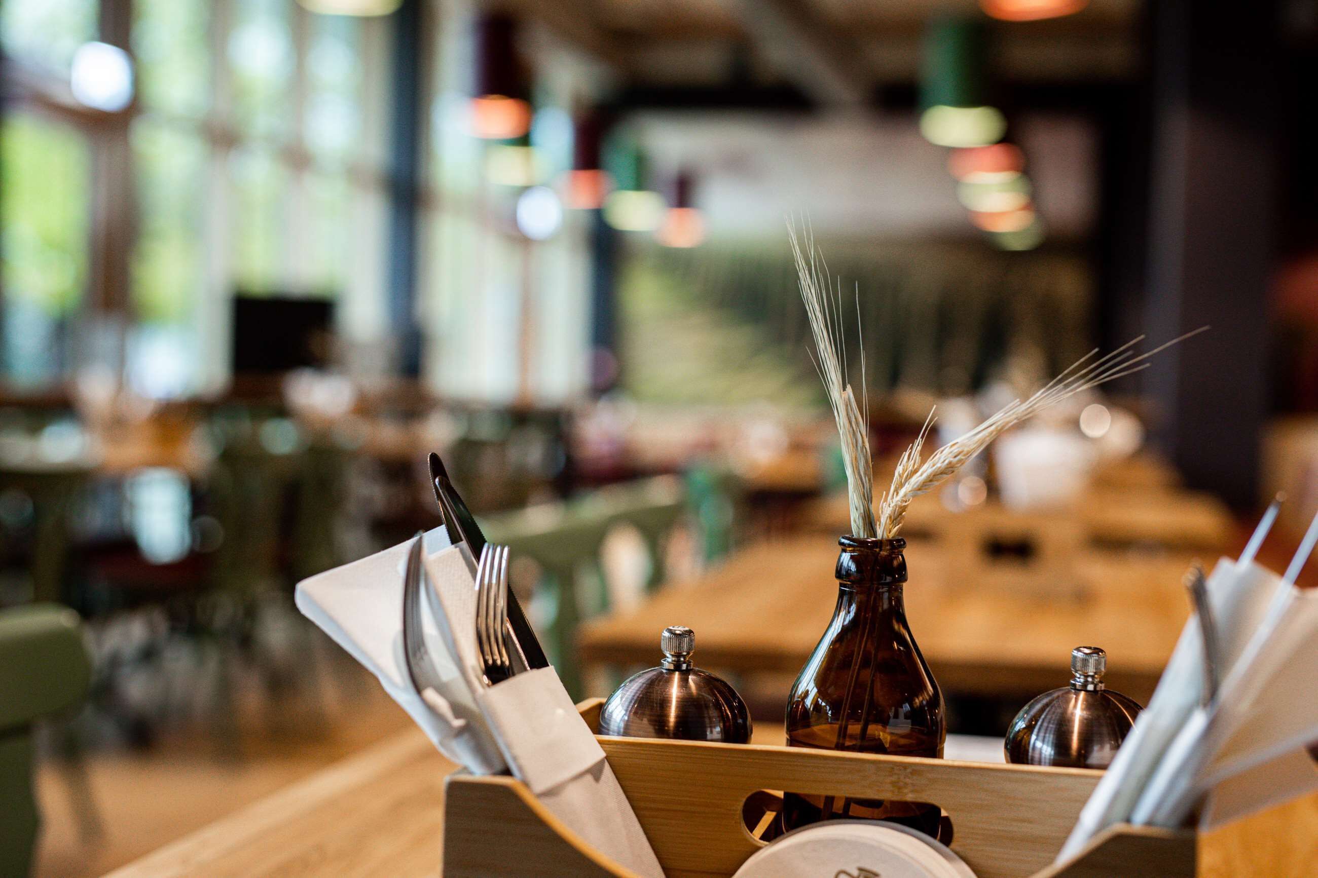 A dining area with a wooden table, a vase with a decorative reed, and a bottle of sauce.