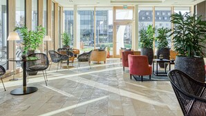 Un hall d’entrée spacieux, doté de grandes fenêtres, de meubles modernes et de plantes en pot.