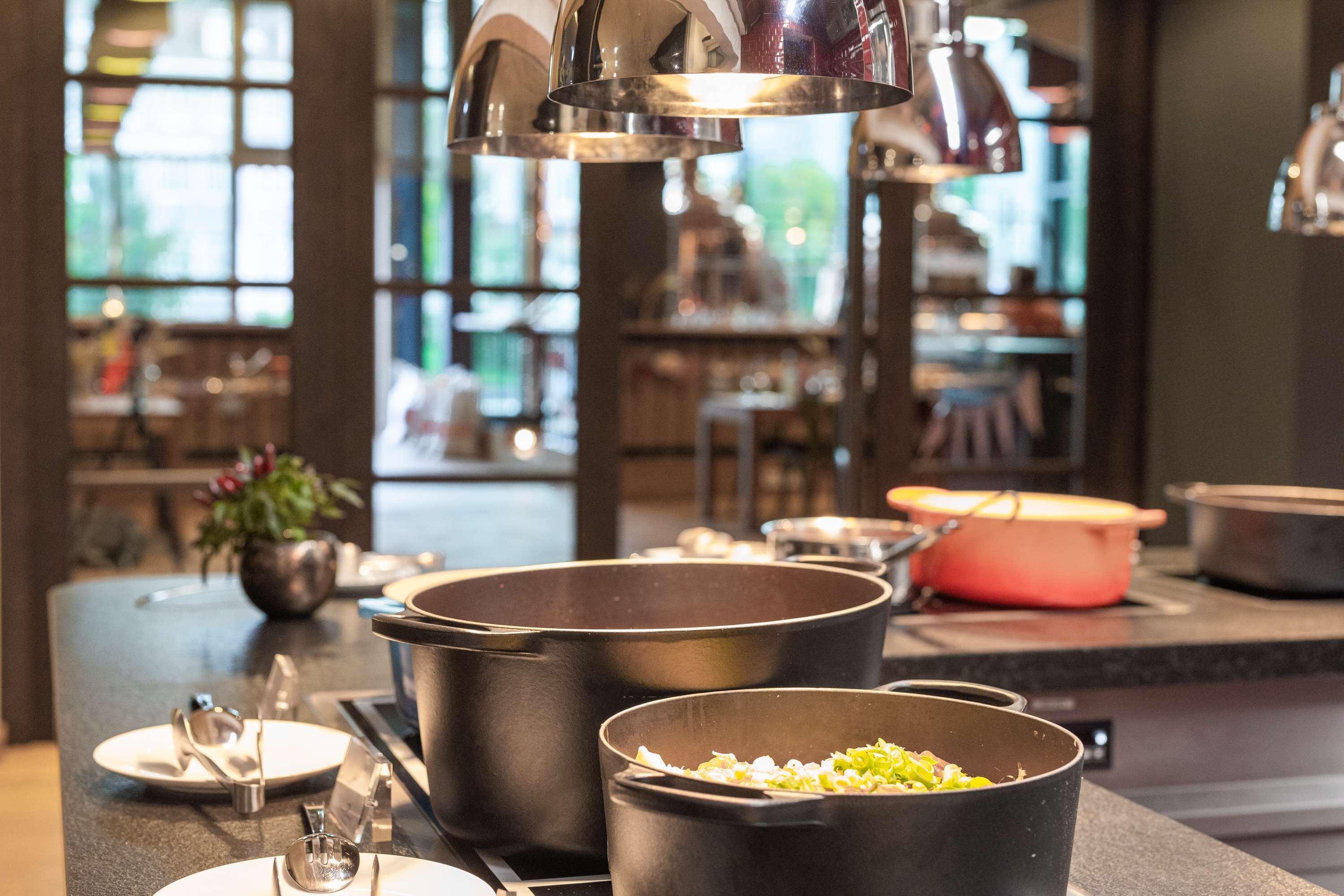 Eine Küchenzeile mit großen Töpfen auf dem Herd, einem Spülbecken und einer Arbeitsplatte mit Küchenutensilien.