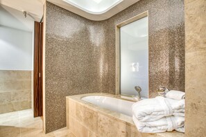 A modern bathroom with a large bathtub, a glass shower enclosure, and a mirror reflecting the room. - Parkhotel Heilbronn (Heilbronn)