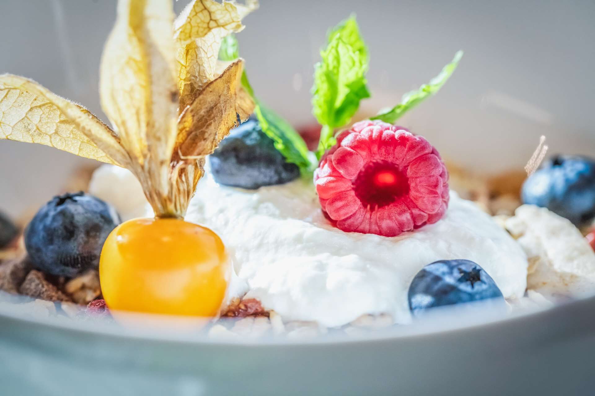 A dessert plate with whipped cream, raspberries, blueberries, and a yellow fruit.