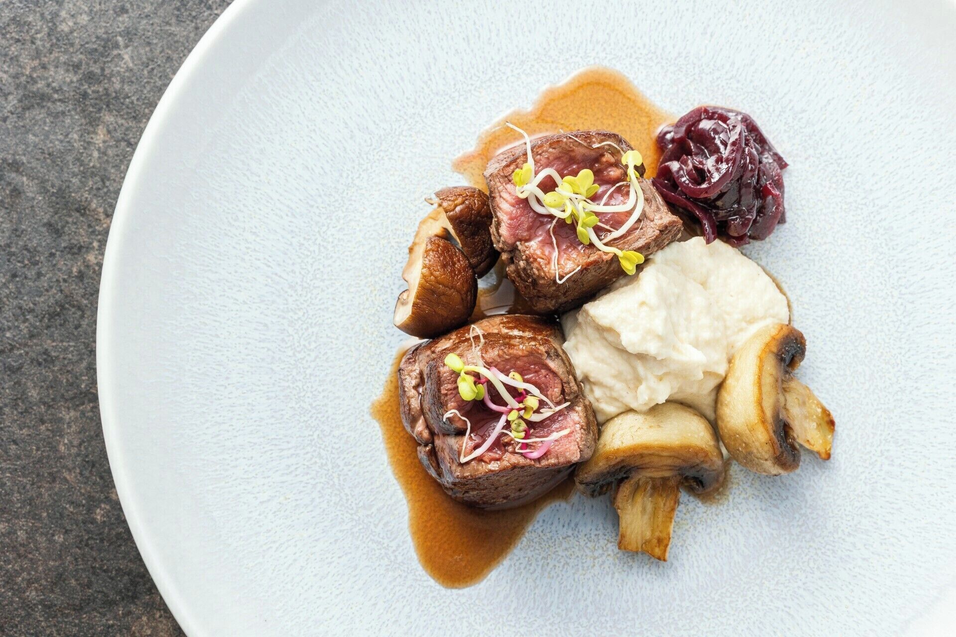 En tallerken med et måltid bestående af kød, svampe og en cremet sauce.