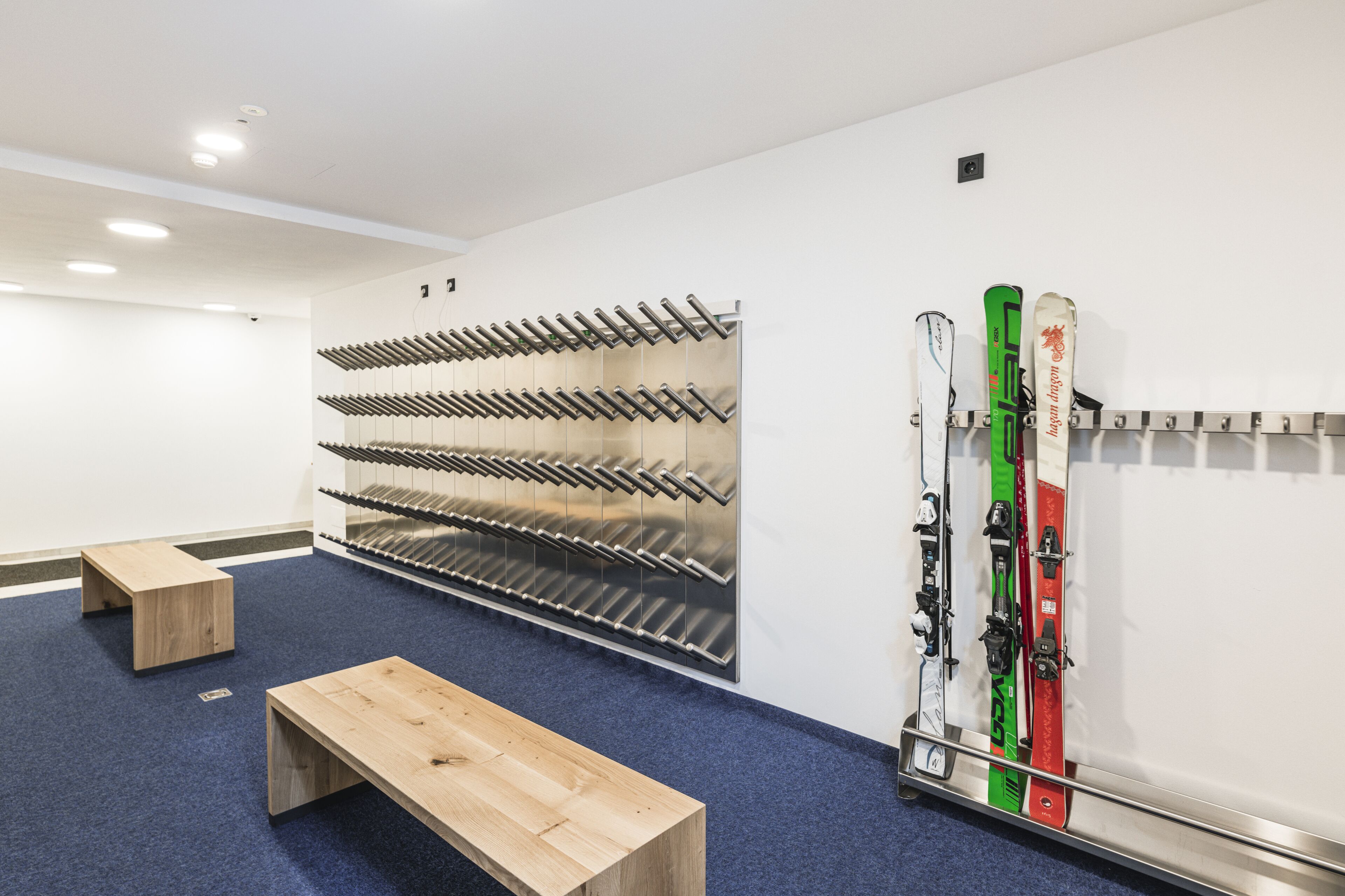 A ski storage area with a wall-mounted rack and a bench.