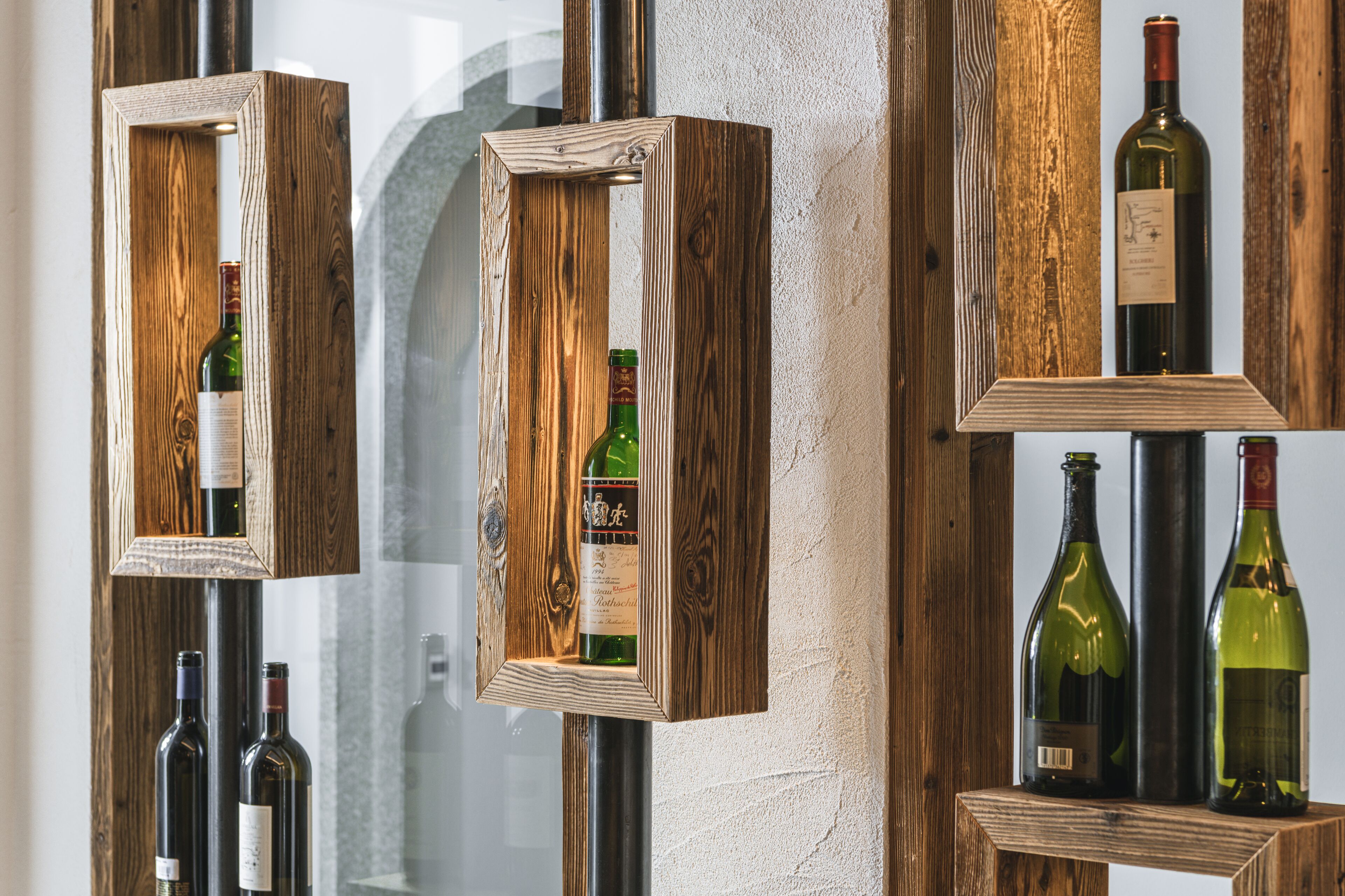 Wijnrekken van hout met flessen voor een ruwe wand.