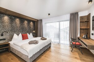 Un dormitorio moderno con una cama grande, un escritorio de madera y una pared de piedra.