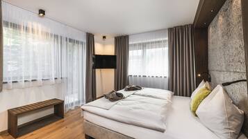 Una habitación de hotel moderna con una cama grande, un banco y un televisor de pantalla plana.
