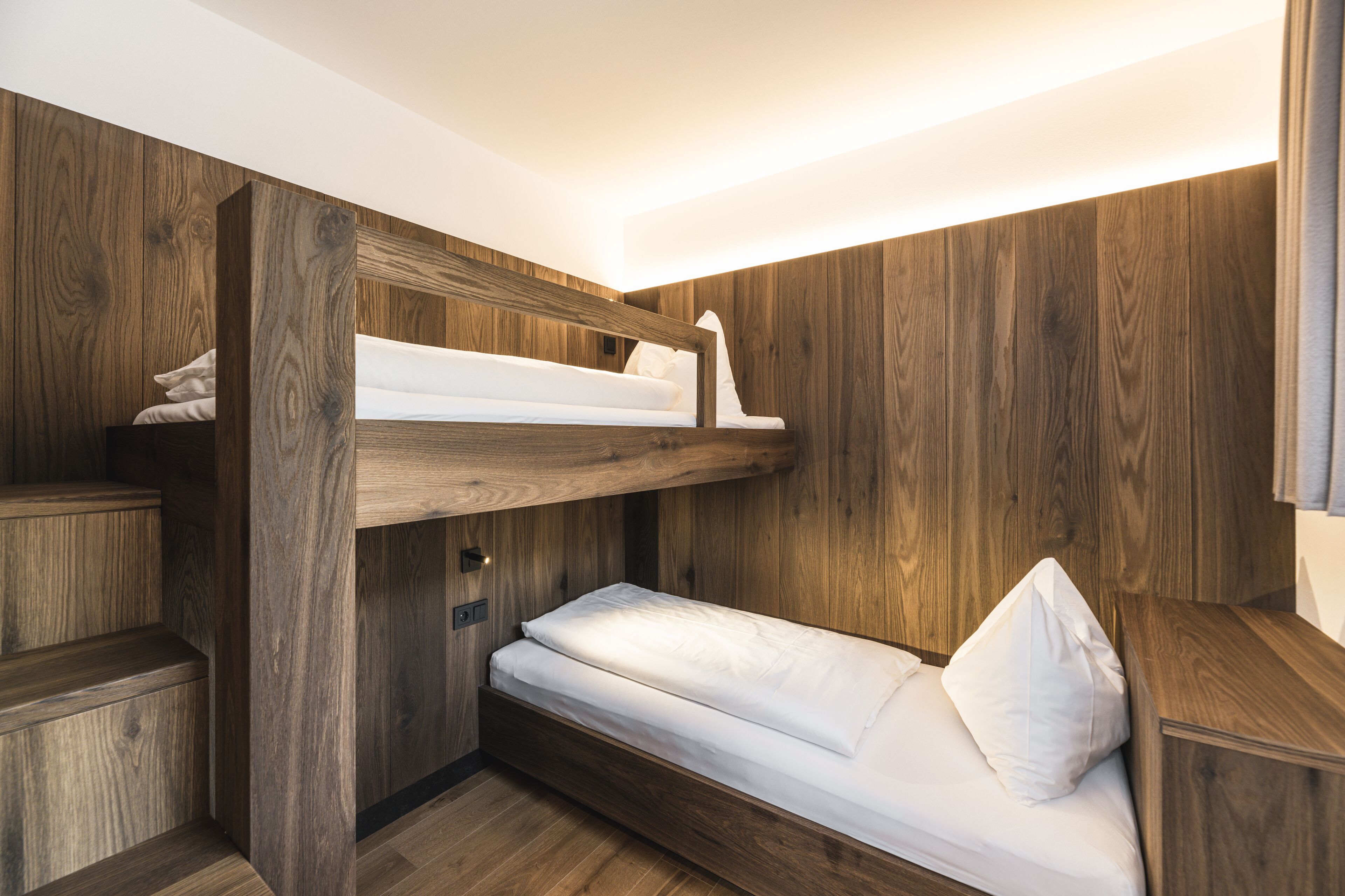 Une chambre avec un lit superposé, des murs en bois et une étagère intégrée.