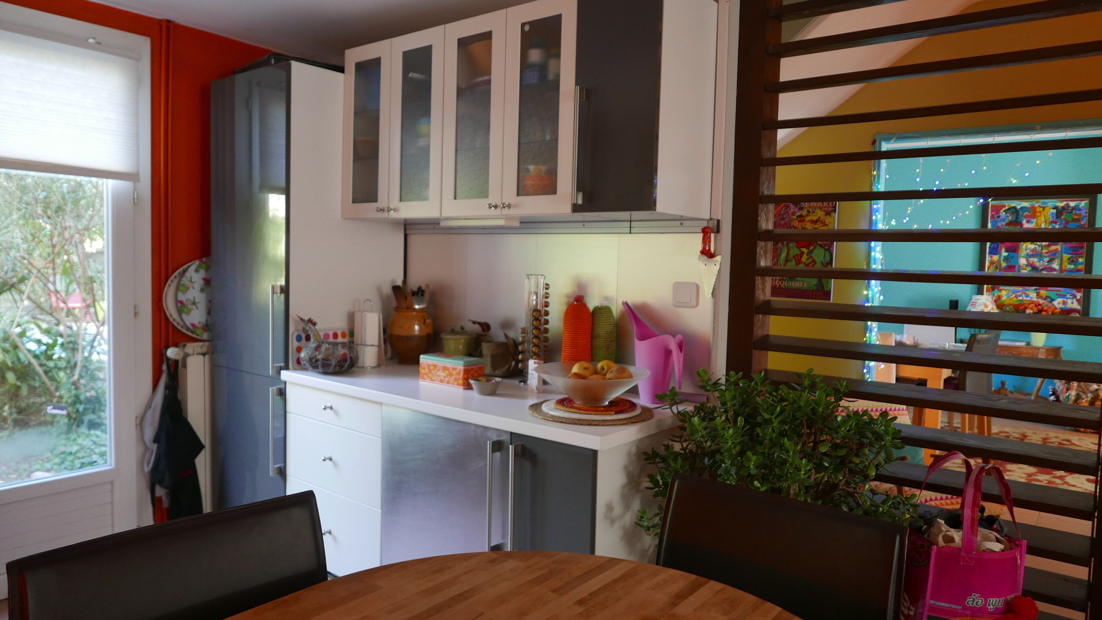 Una cocina con armarios blancos, un refrigerador y una mesa de comedor con sillas.