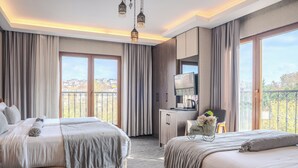 Habitación de hotel con dos camas, un escritorio, un televisor y un balcón con vistas.