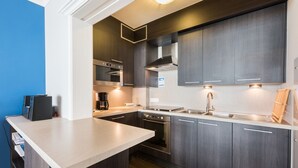 Una cocina moderna con armarios oscuros, electrodomésticos de acero inoxidable y una encimera de color claro.