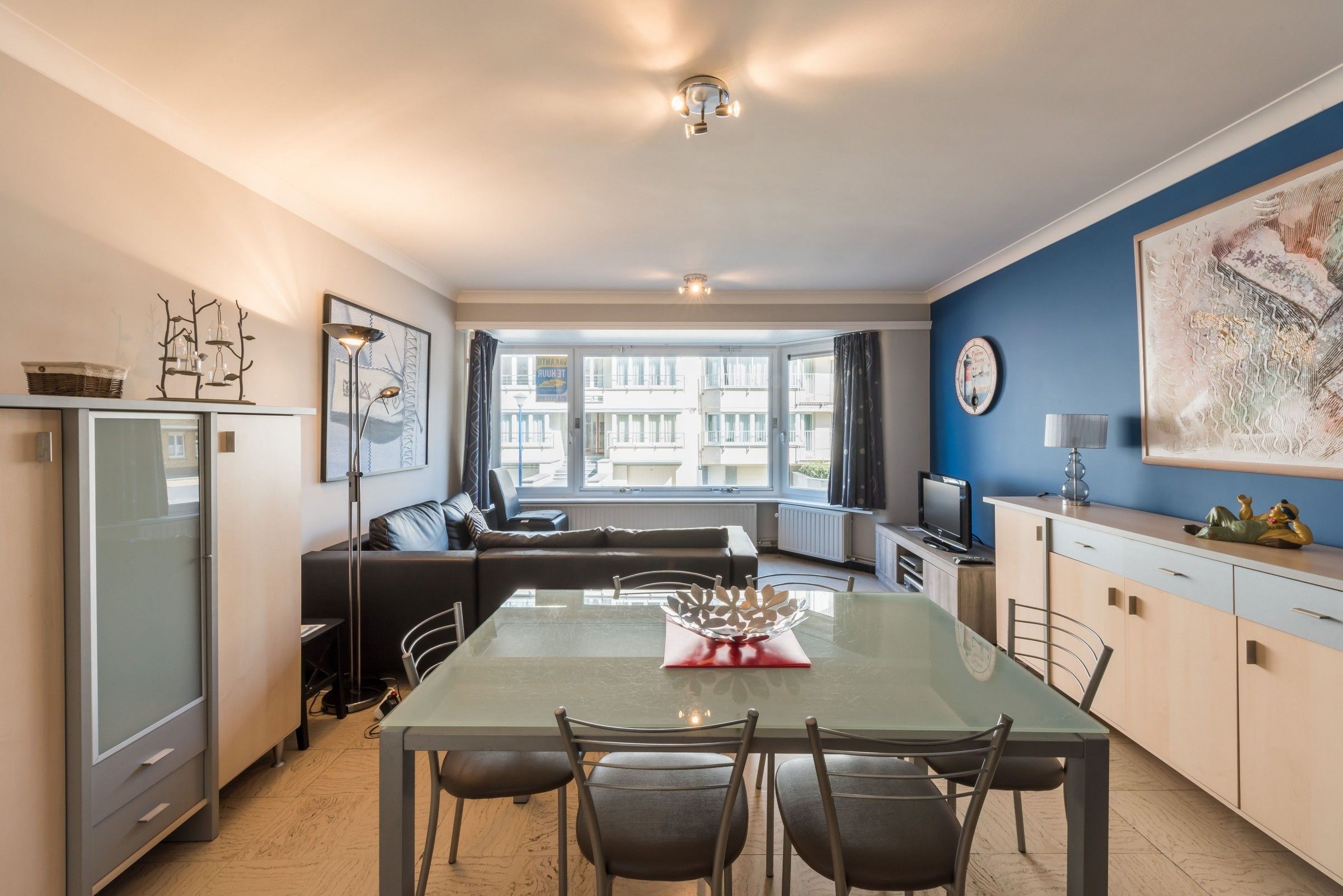 A modern kitchen with a dining table, chairs, and a refrigerator.
