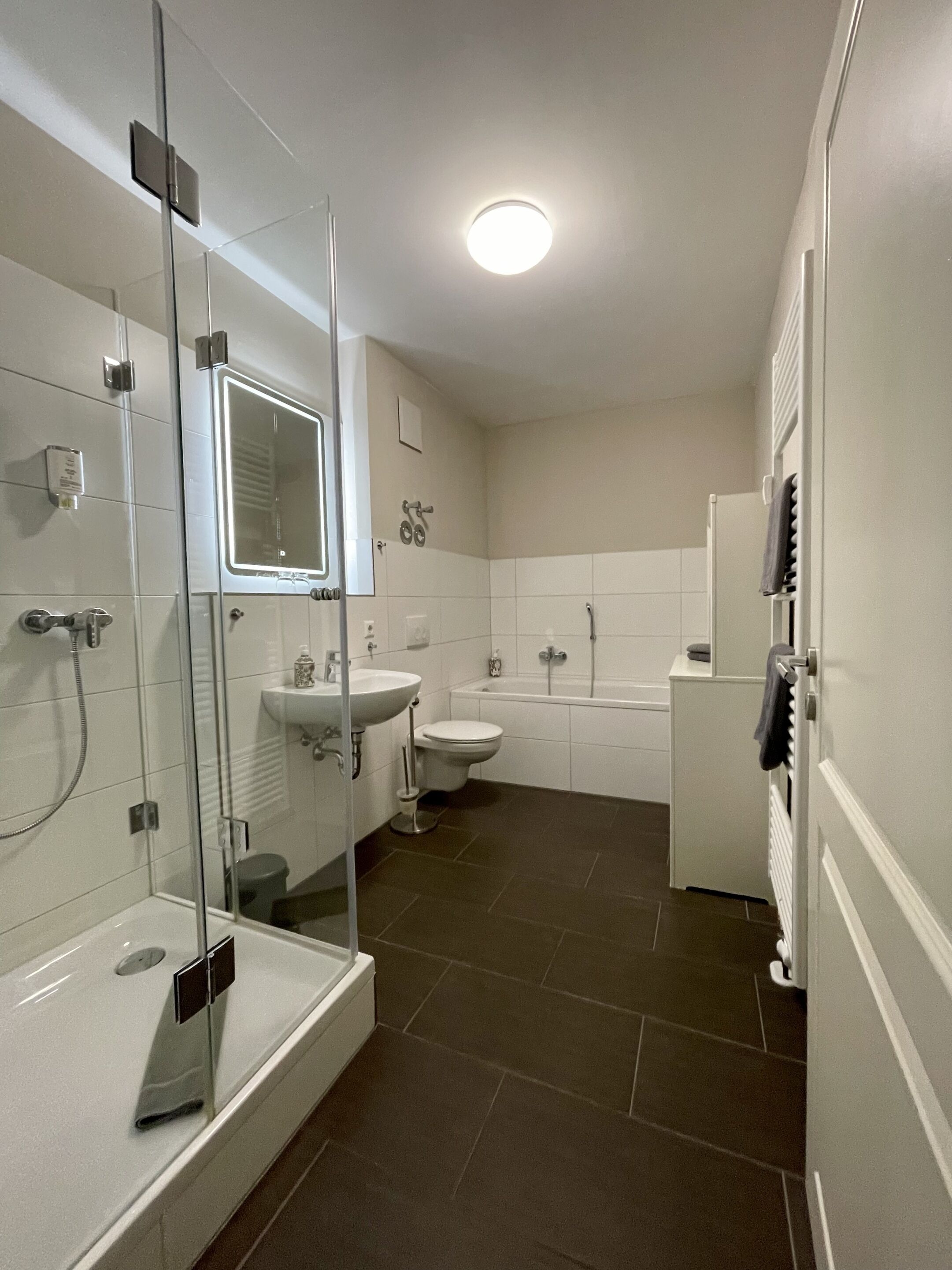 A modern bathroom with a glass-enclosed shower, a white sink, a toilet, and a bathtub.
