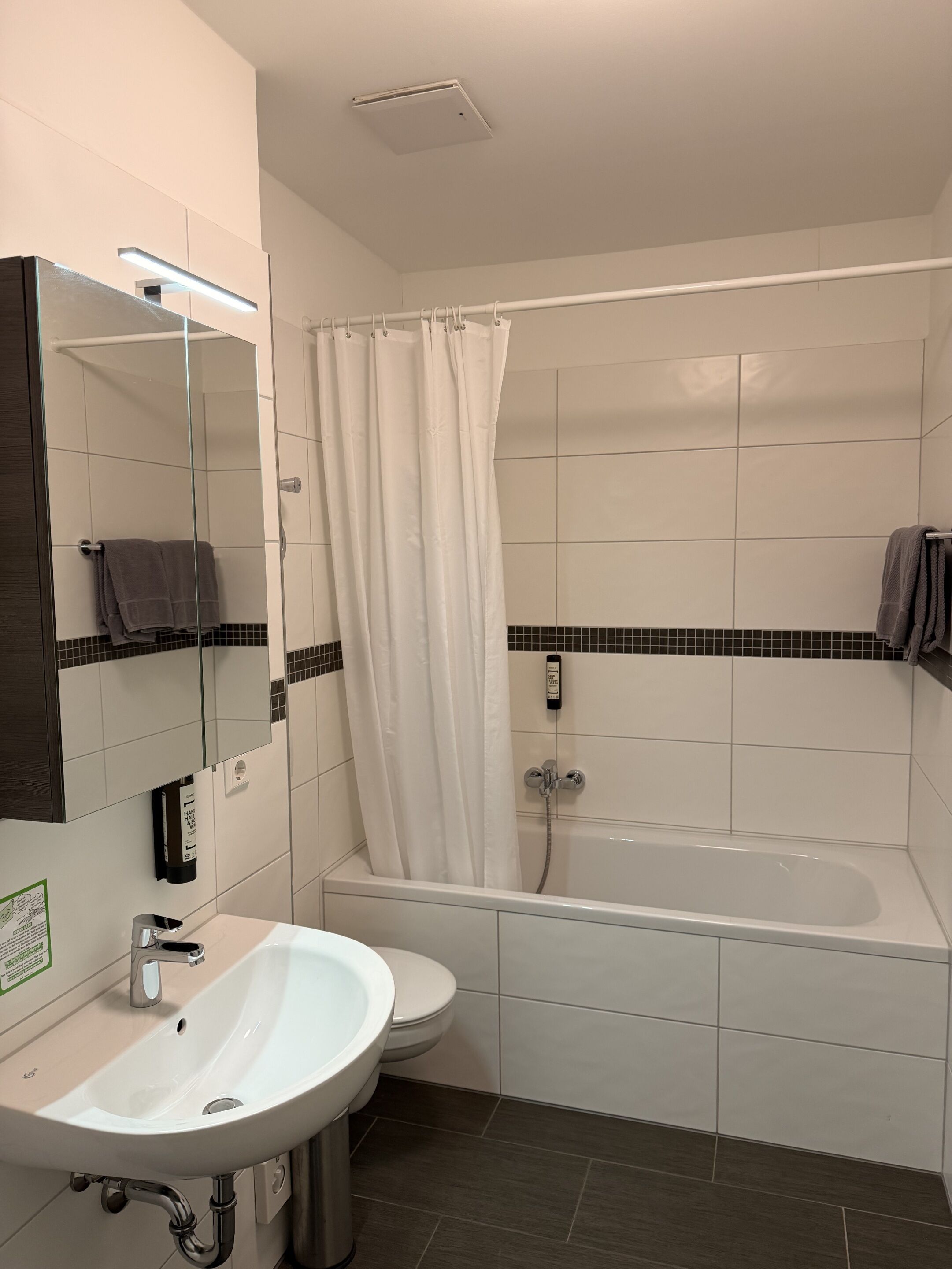 A modern bathroom with a white sink, toilet, and bathtub.