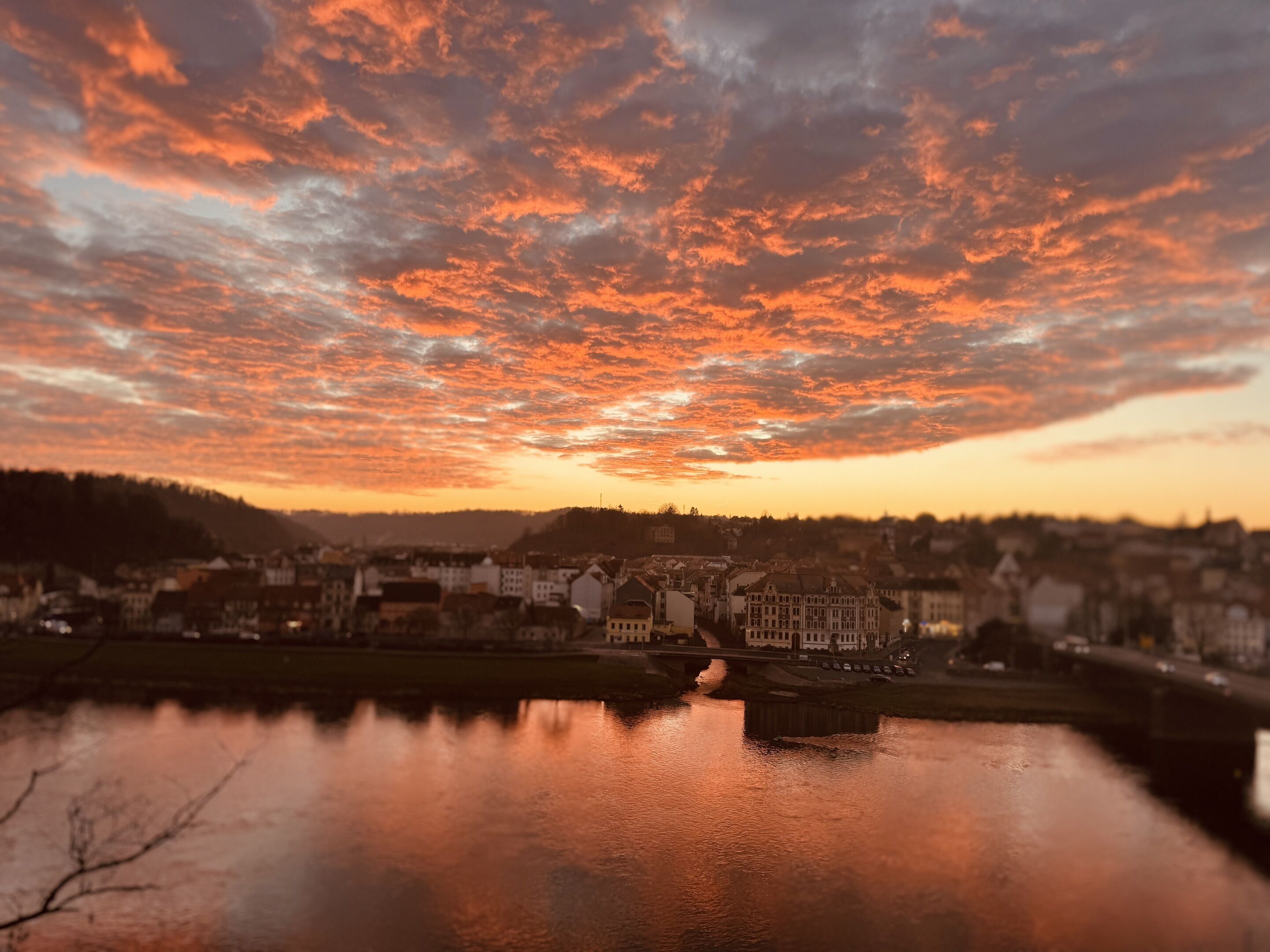 A cityscape with a river reflecting the sunset sky.