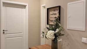 A hallway with a wooden bench, a framed inspirational quote, and a vase with flowers. - Pension Burkhardt (Meissen)