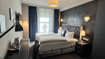Een hotelkamer met een bed, bureau, stoel, lamp en uitzicht op de omgeving.