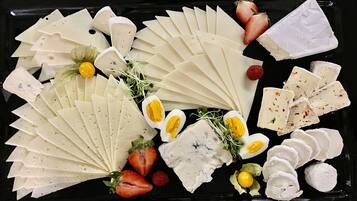 A variety of cheeses and fruits arranged on a black tray.