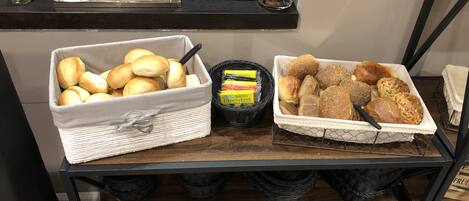 A breakfast buffet with various breads and pastries.