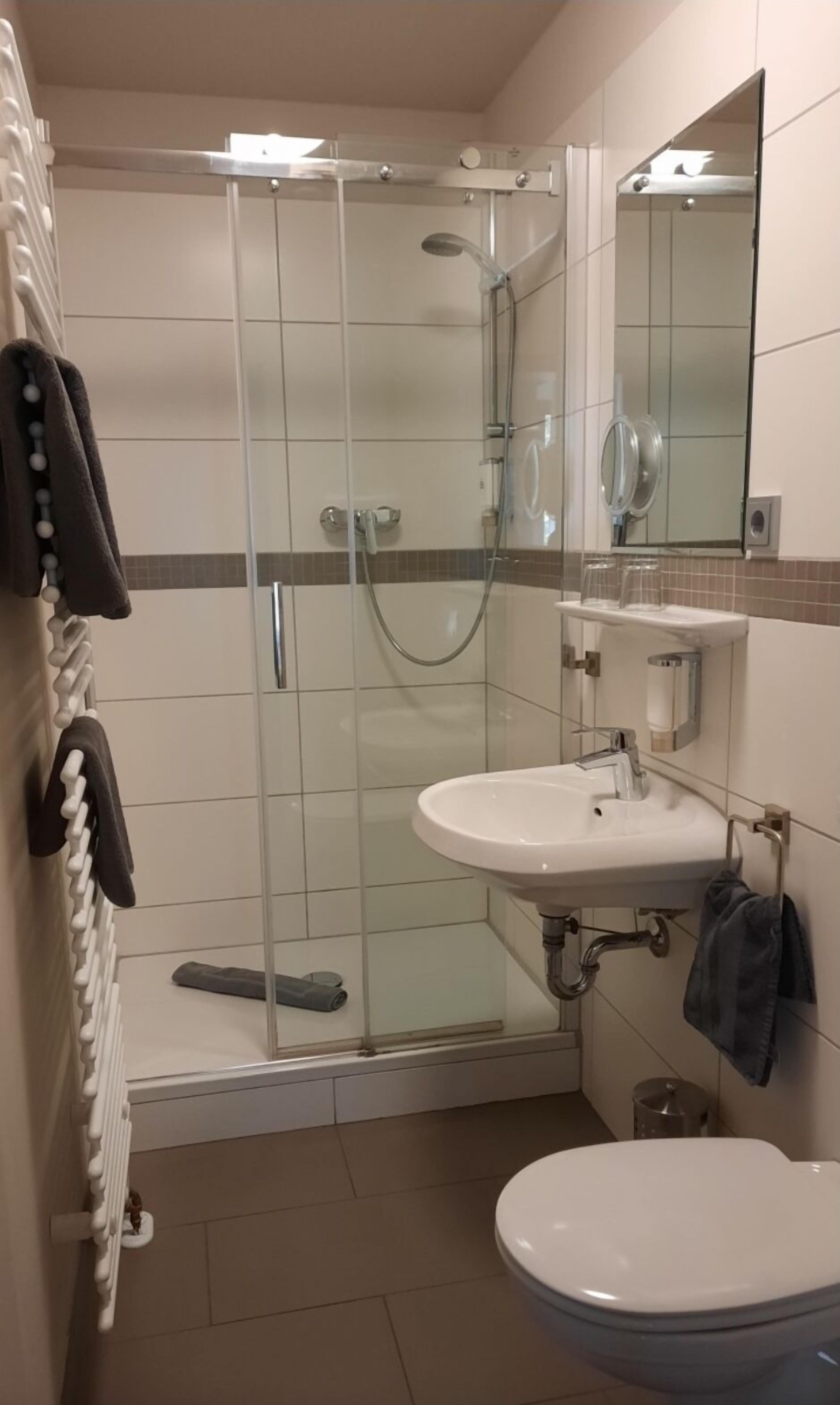 Ein modernes Badezimmer mit einer Duschkabine, einem weißen Waschbecken und einer Toilette.