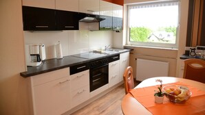 A modern kitchen with white and black cabinets, a black countertop, and a window with a view of greenery outside.