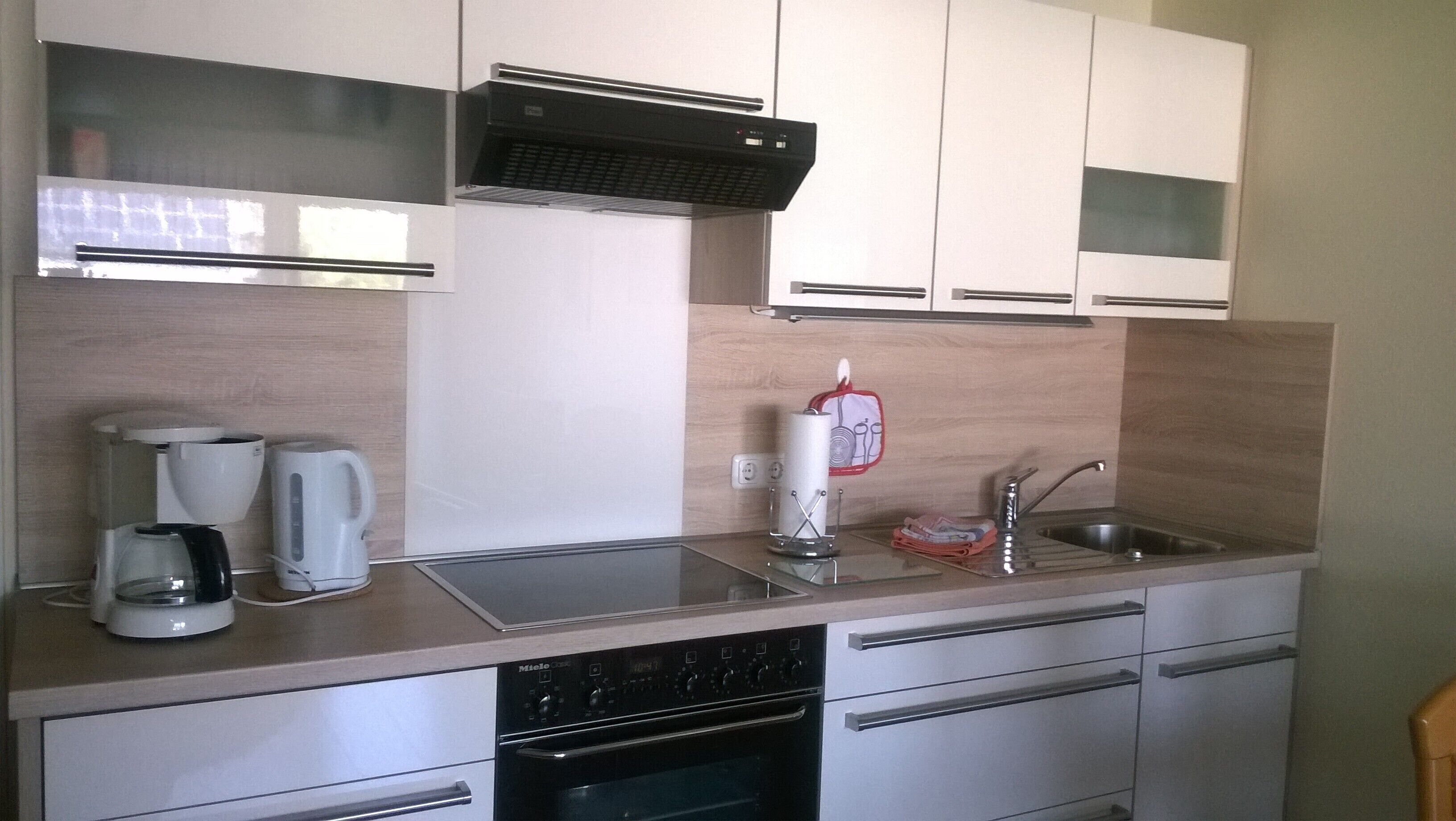 A modern kitchen with a dishwasher, coffee maker, and kettle.
