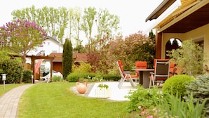 A well-maintained garden with a patio area, outdoor furniture, and a pathway leading to a house.