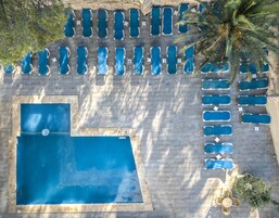 Vista aérea de un área de piscina con múltiples sillones de descanso y una piscina grande.